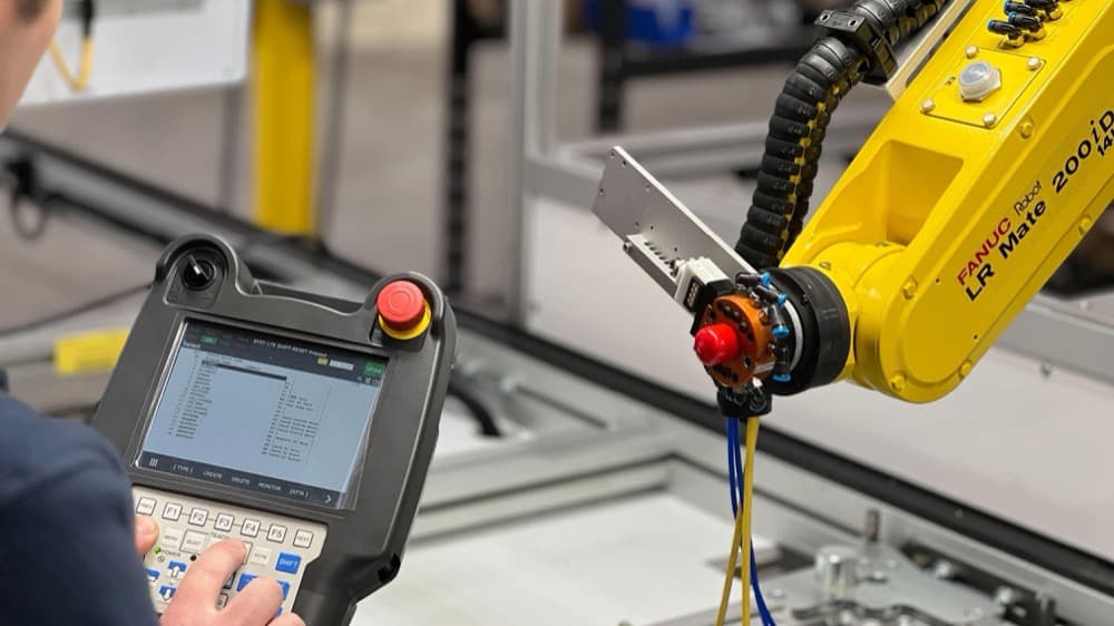 An engineer programming a FANUC LR Mate robot from a teach pendant