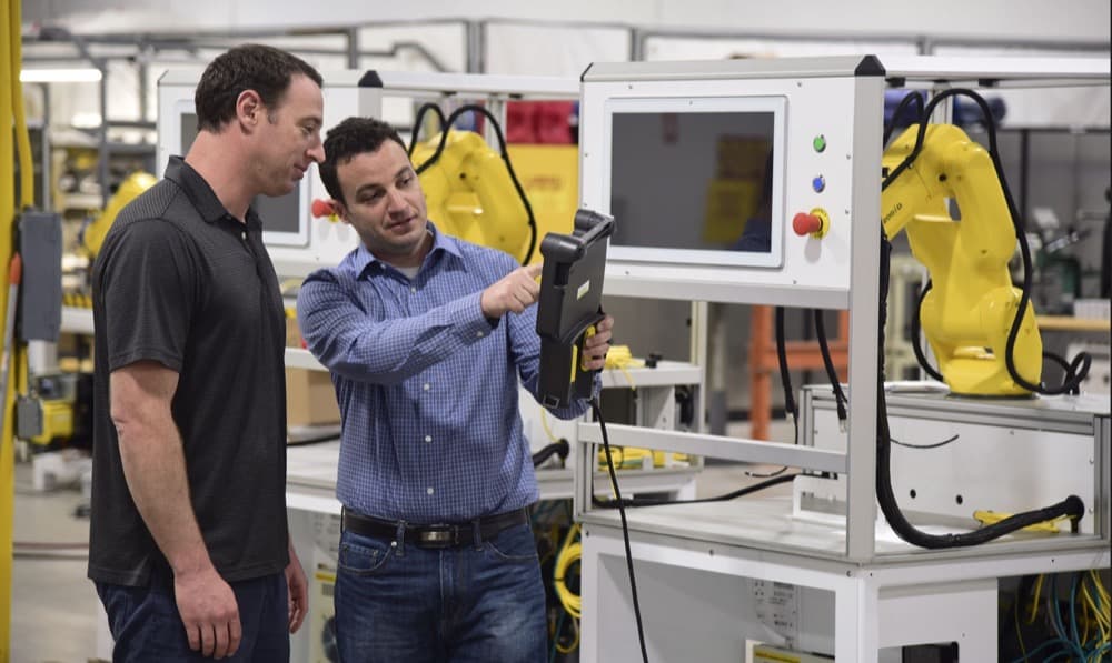 Two Flexible Assembly engineers programming a robot cell on site